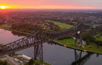 (© sh-tourismus.de / MOCANOX) Luftaufnahme der Rendsburger Hochbrücke und des Nord-Ostsee-Kanals bei Sonnenuntergang