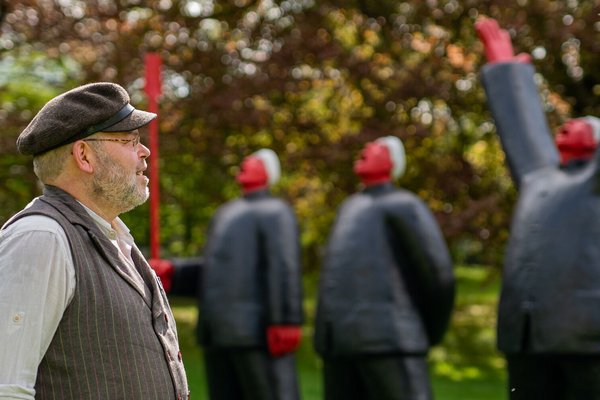 Tipps für einen Kurzurlaub (©sh-tourismus.de/MOCANOX) Ein Mann steht vor einer Kunstinstallation. menschliche Figuren stehen im Hintergrund, die Natur ist grün.